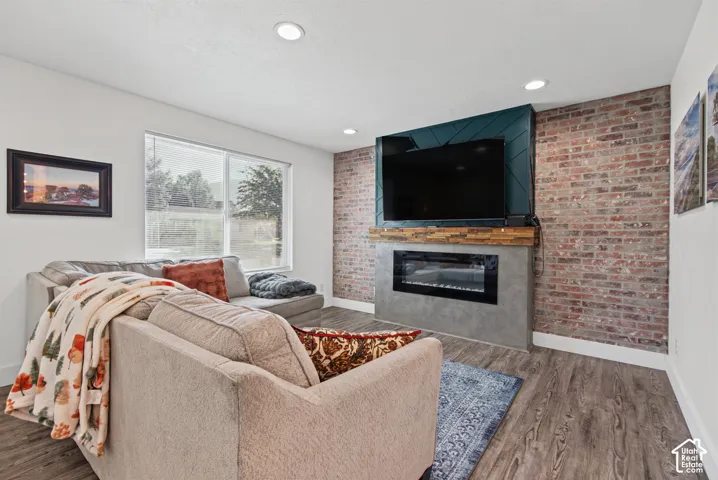 Recessed lighting,  and a brick accent wall with a built-in fireplace featuring a wood mantel
