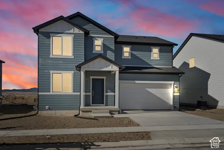 Two-story residence featuring blue siding with white trim, a covered entry, an attached two-car garage, and a concrete driveway