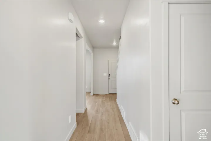 Hallway featuring wood-finish flooring, recessed lighting, and white paneled doors