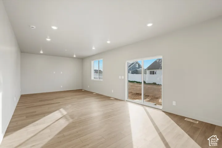 Recessed lighting, wood-finish flooring, light-toned walls, and a sliding glass door