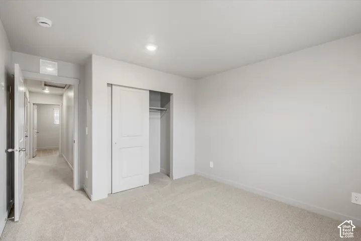 Light-toned wall paint with coordinating trim, neutral carpet flooring, recessed ceiling lighting, and a sliding two-panel closet door