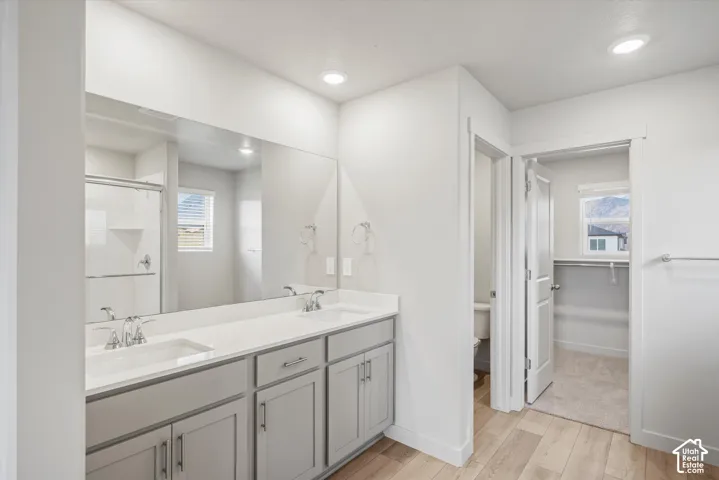 Dual sink vanity with light-toned cabinetry, an integrated countertop, and a large wall-mounted mirror