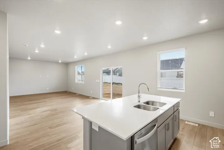 Kitchen island with a dual basin sink, stainless steel appliances, and white countertop