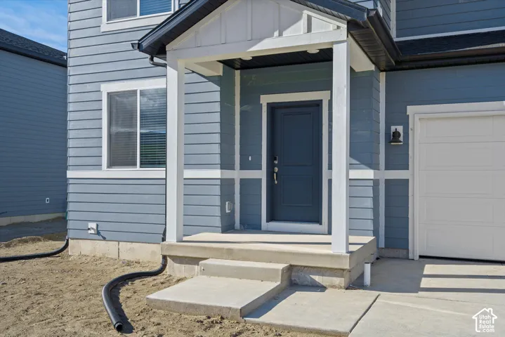 Entry porch with a paneled front door, an exterior wall light, and an attached garage with a white sectional door