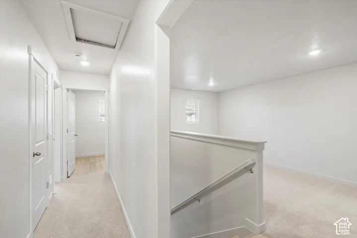 Upper-level landing and hallway with neutral carpeting, white interior doors, recessed lighting, and a white handrail