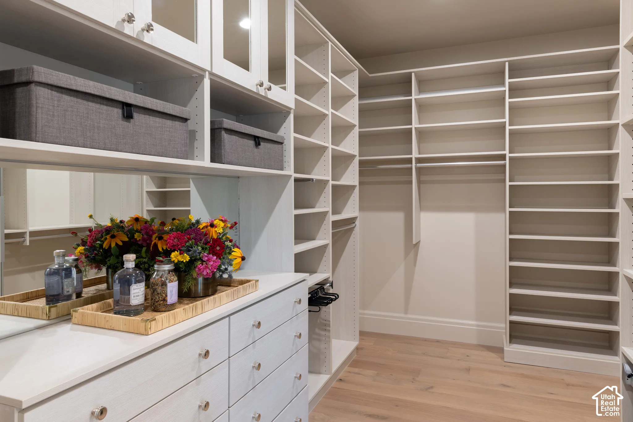 Custom closet system featuring extensive shelving, built-in drawers, hanging rods, mirrored accents, and wood-finish flooring