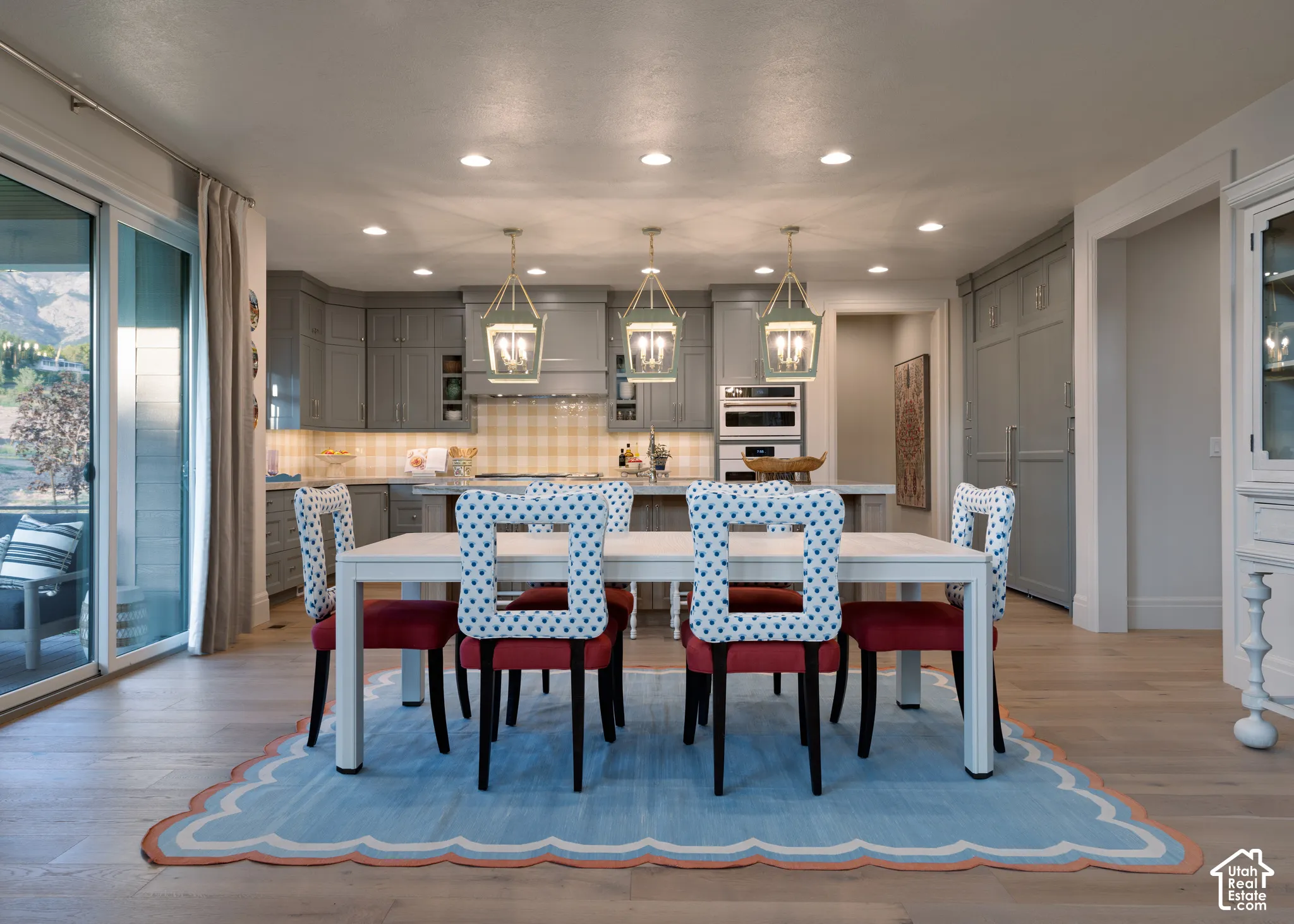 Recessed ceiling lighting, wood-finish flooring, glass sliding door, and a built-in kitchen with integrated appliances and pendant lighting