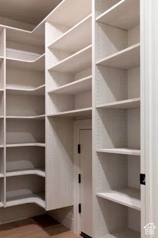 Extensive built-in shelving with adjustable shelves, light wood-finish cabinetry, and wood-finish flooring