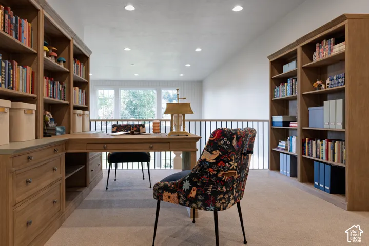 Built-in wood-finish shelving, integrated desk, recessed lighting, and carpeting