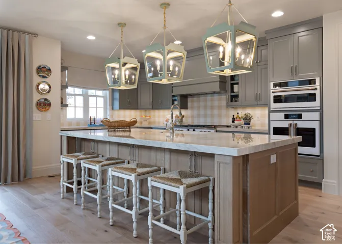 Kitchen featuring a light-toned wood-finish island with a stone countertop, built-in stainless steel appliances, and gray cabinetry