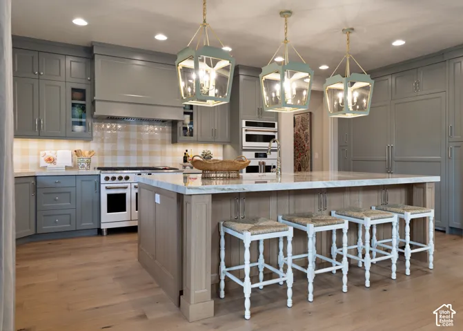 Spacious kitchen featuring gray cabinetry, a large center island with a light-toned countertop, and wood-finish flooring