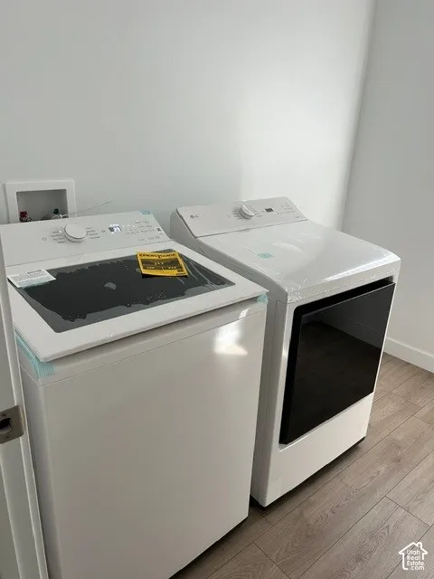 Laundry area with wood-finish flooring, white walls, and new appliances