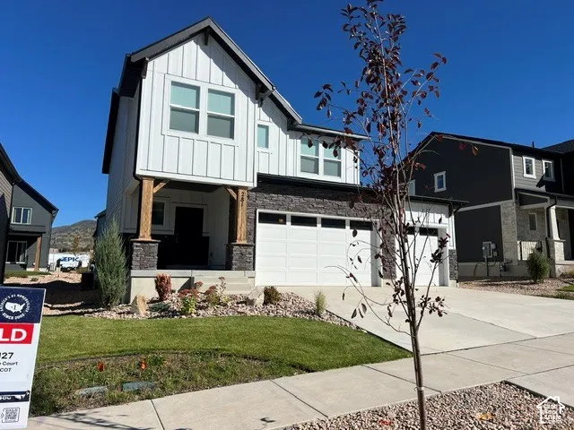 Two-story exterior with board and batten siding, stone facade, and a two-car garage