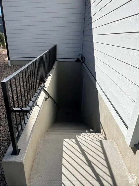 Concrete basement entry with black metal railings and horizontal siding exterior
