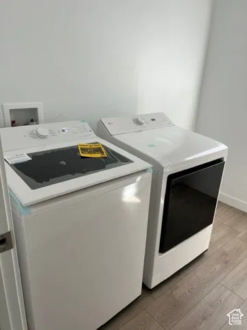 Laundry area with wood-finish flooring, white walls, and new appliances