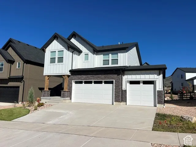 Modern two-story exterior with white vertical siding and dark stone accents