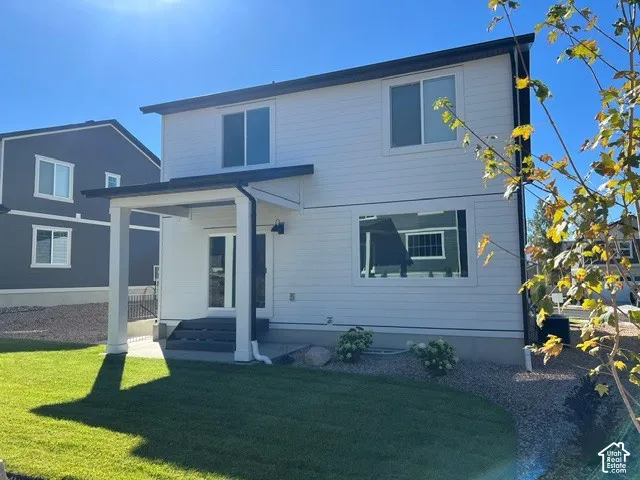 Two-story exterior with white siding, covered patio with white columns, and a manicured lawn
