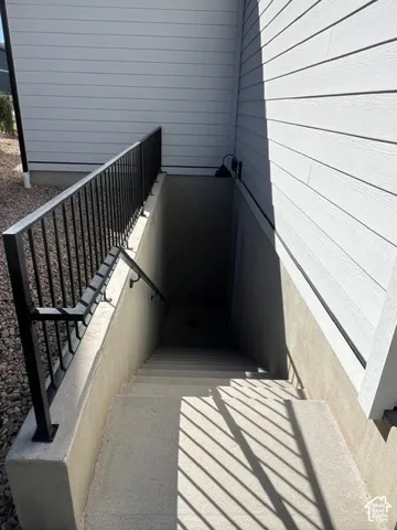 Concrete basement entry with black metal railings and horizontal siding exterior