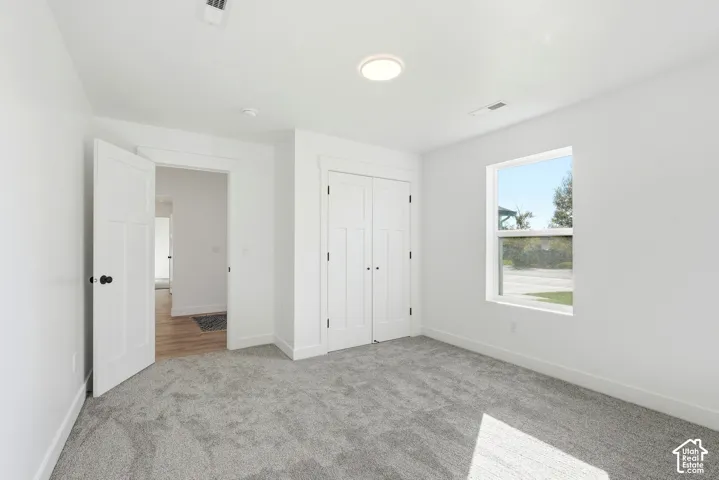 Recessed lighting, light gray carpeting, white walls, and a window with white trim