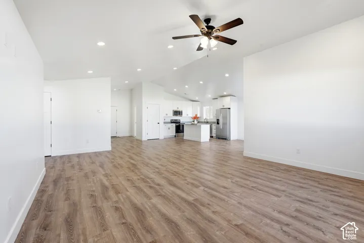 Open-concept living space featuring wood-finish flooring, recessed lighting, and a vaulted ceiling with a ceiling fan