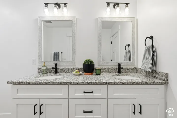PRIMARY BATHROOM-Dual vanity featuring white shaker-style cabinetry, dark hardware, and integrated sinks