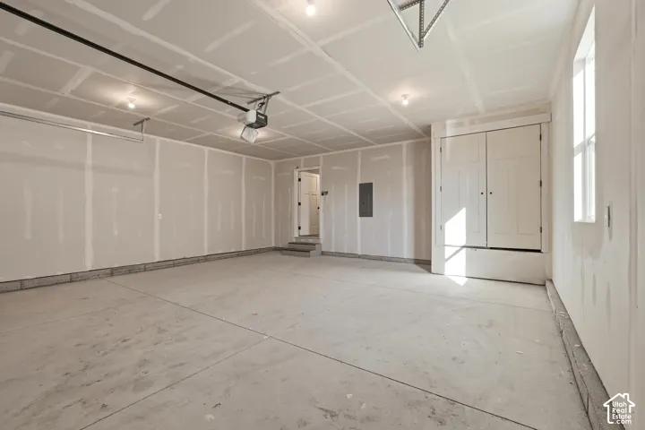 Spacious garage with concrete flooring, built-in storage, and multiple windows