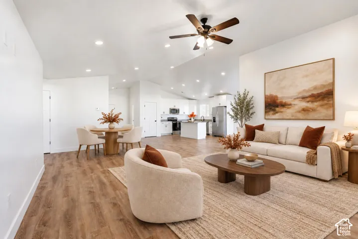 Vaulted ceilings with a ceiling fan, recessed lighting, wood-finish flooring, and a kitchen featuring a central island and stainless steel appliances
