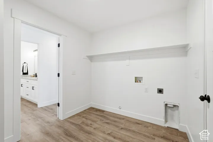 Laundry area featuring wood-finish flooring, white walls, and a built-in shelf