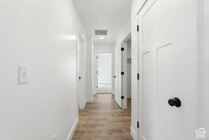 Wood-finish flooring throughout, white interior doors with dark hardware, and recessed lighting