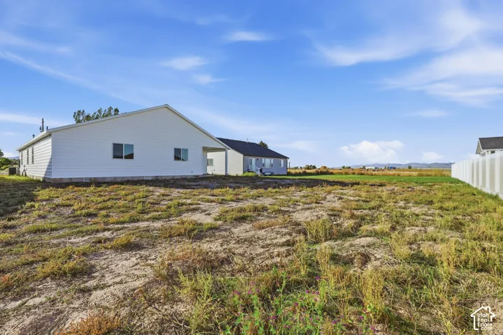 Expansive undeveloped lot with partial white privacy fence and distant mountain range