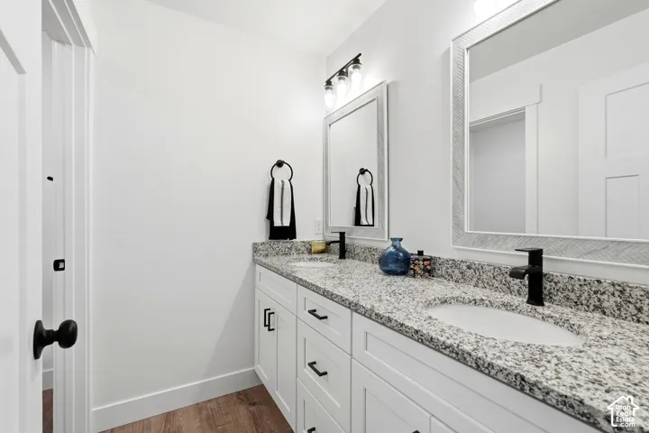 Dual vanity with granite countertops, white cabinetry, and matte black fixtures