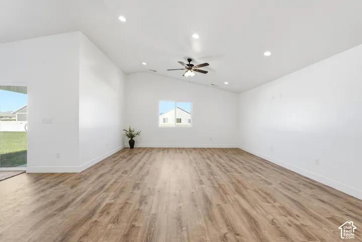 Spacious interior featuring wood-finish flooring, vaulted ceilings, recessed lighting, and a ceiling fan