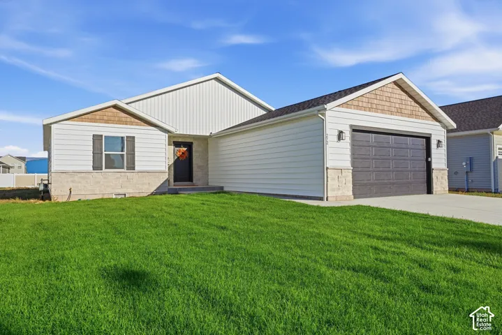 Contemporary ranch-style exterior with light-colored siding, a dark paneled garage door, stone veneer accents, and a gabled roofline