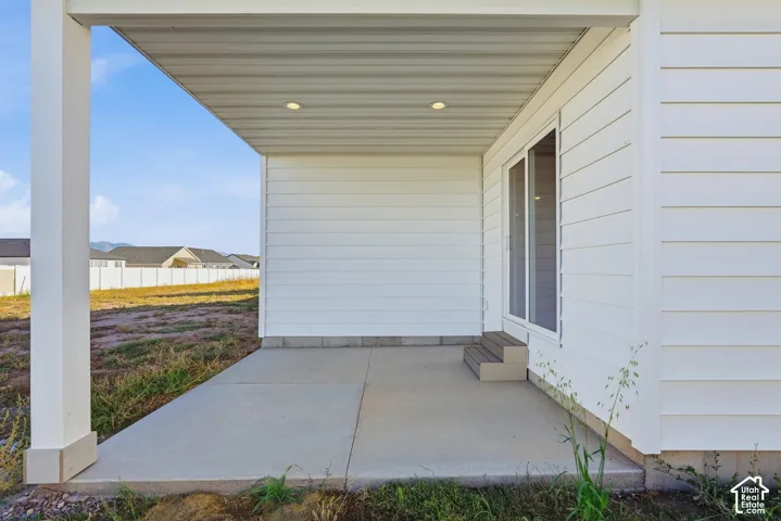 Covered concrete patio with recessed lighting, white siding, and a sliding glass door