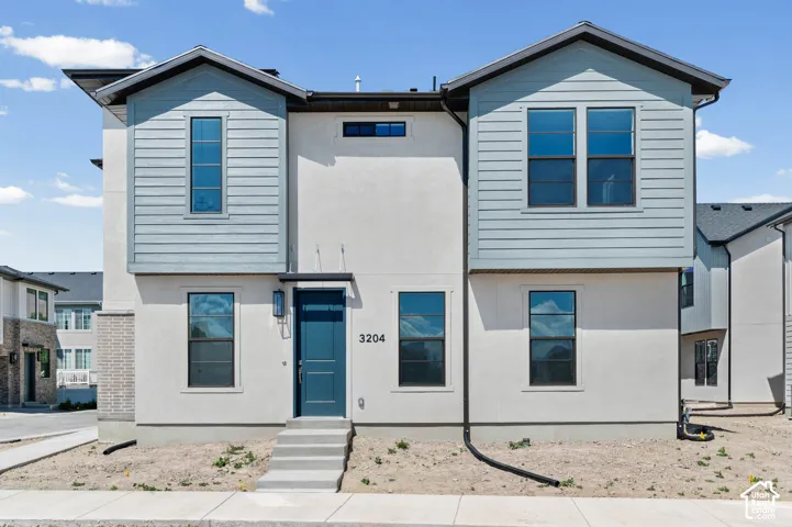 Modern townhome exterior with light-colored stucco and light blue horizontal siding accents