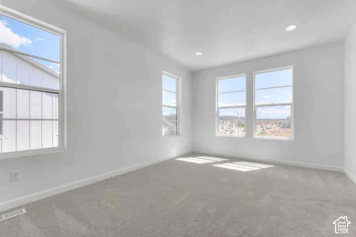 Spacious room with four windows, recessed lighting, white walls, and light-colored carpeting