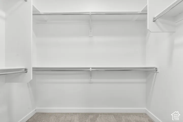 White shelving system with chrome hanging rods and carpet flooring