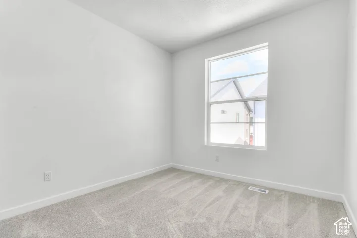 Neutral wall paint, light-colored carpeting, single window with white frame