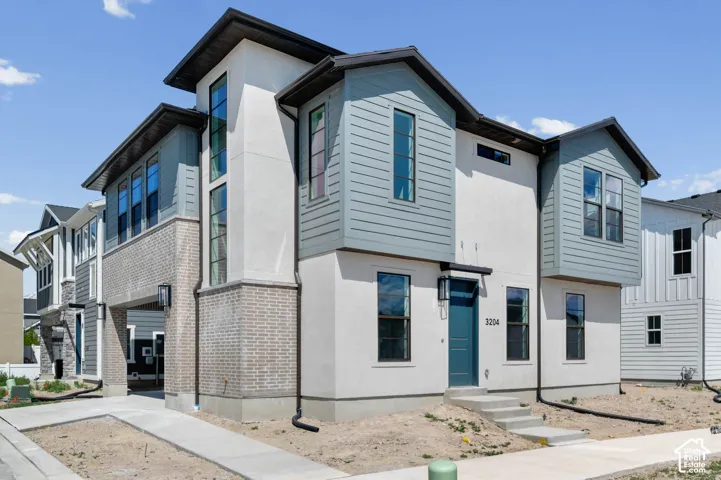 Contemporary multi-level exterior with board and batten siding, horizontal plank siding, brick veneer accents, and an integrated entryway light fixture