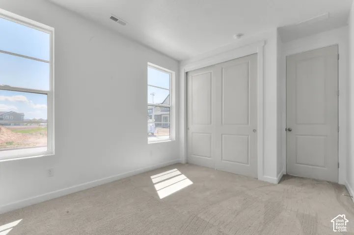 Two windows with white frames, wall-to-wall carpeting, and white walls