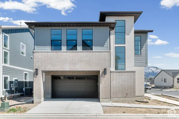 Contemporary exterior featuring light brick, gray siding, and a vertical window arrangement