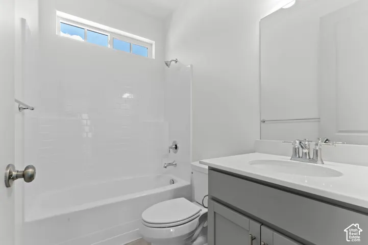 Bathroom featuring a white subway tile surround, bathtub with shower, vanity with an integrated sink, polished chrome faucet, and overhead window