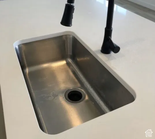 Undermount stainless steel kitchen sink featuring a matte black pull-down faucet set within a white countertop