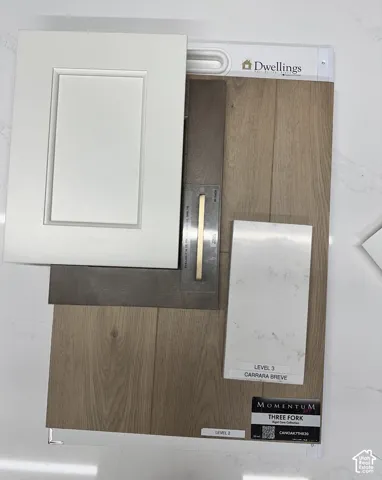 Shaker-style cabinetry in matte white, brushed brass hardware, wood-finish plank flooring, and white quartz surfaces with grey veining
