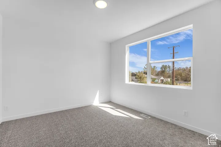 Expansive window with white framing, light gray carpeting, flush-mount ceiling light, and white painted walls