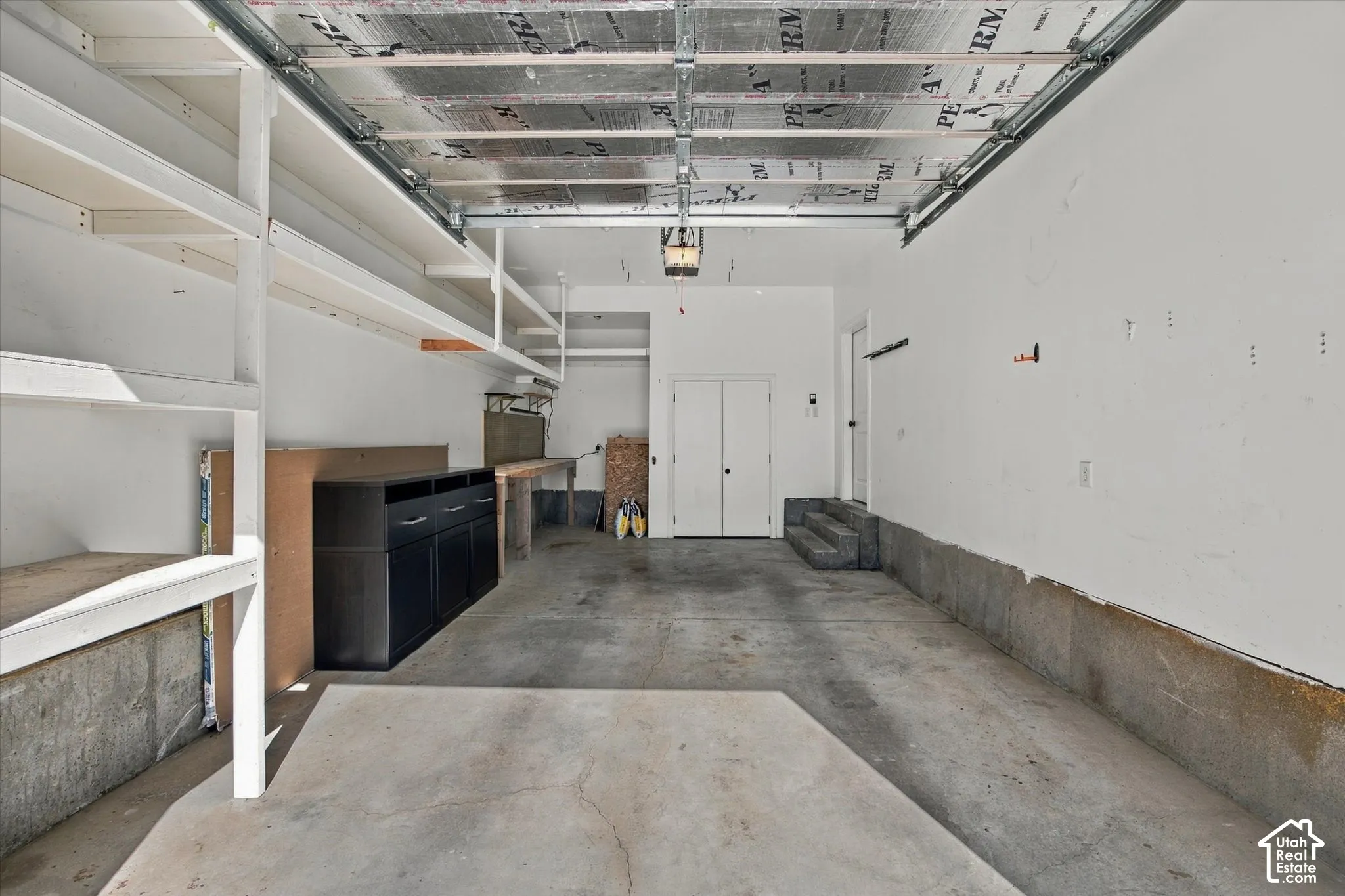 Built-in shelving, concrete flooring, dual entry doors, built-in workbench, and overhead lighting