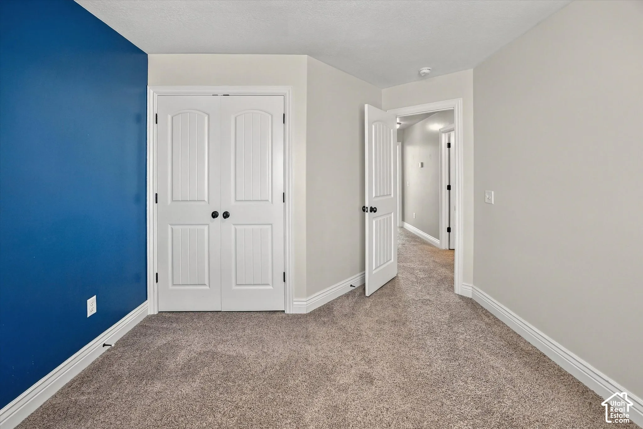 Plush carpeting, interior paneled doors, white trim, and a neutral wall color complement a vibrant accent wall