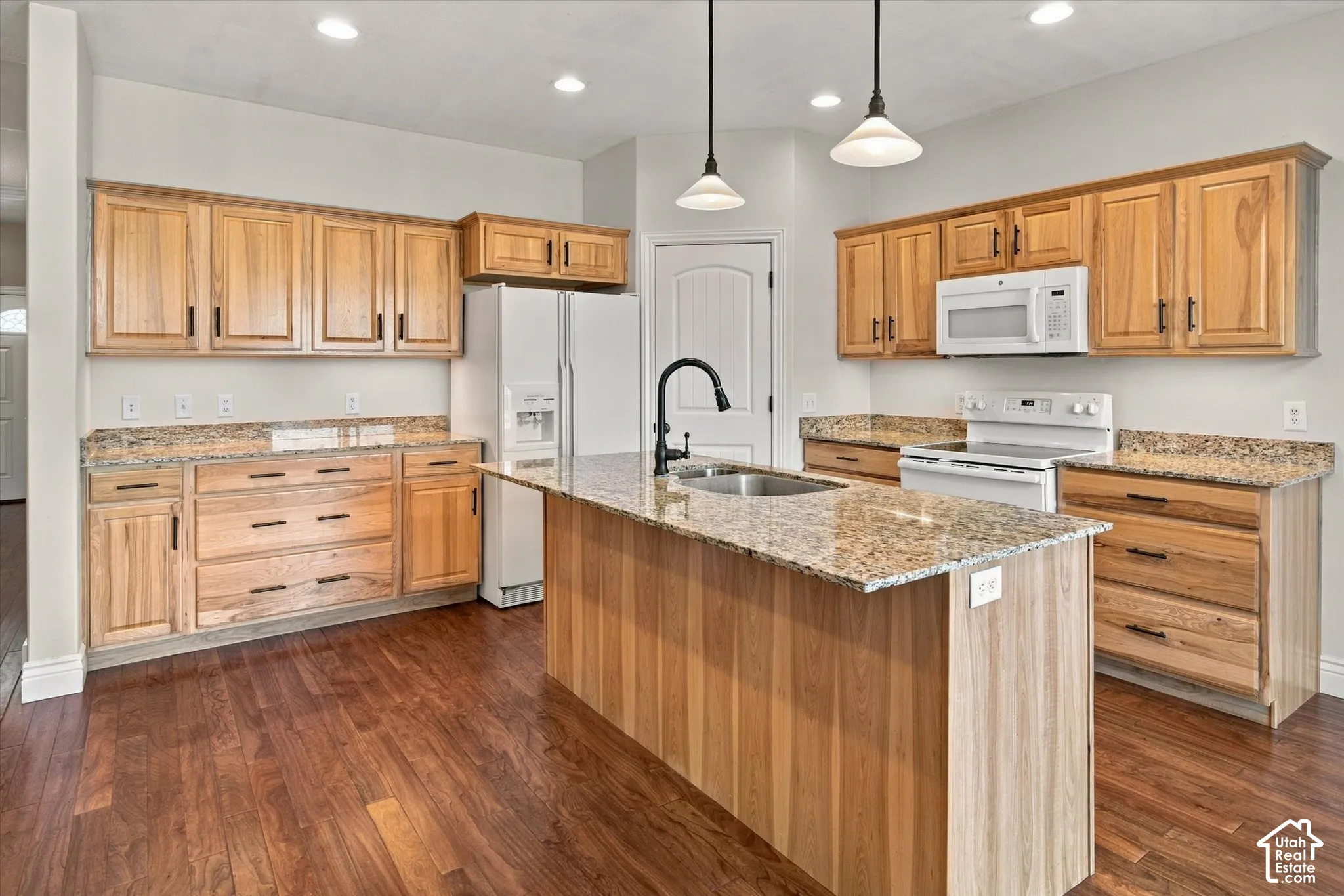 Wood-finish flooring throughout, light wood cabinetry, stone countertops, and a kitchen island with an integrated sink and gooseneck faucet