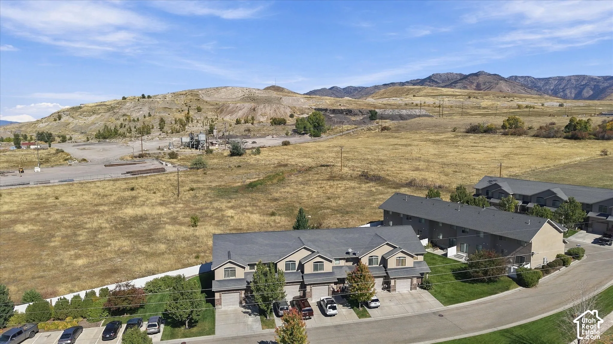 Townhome property featuring a multi-unit structure with attached garages, paved driveways, and a manicured lawn