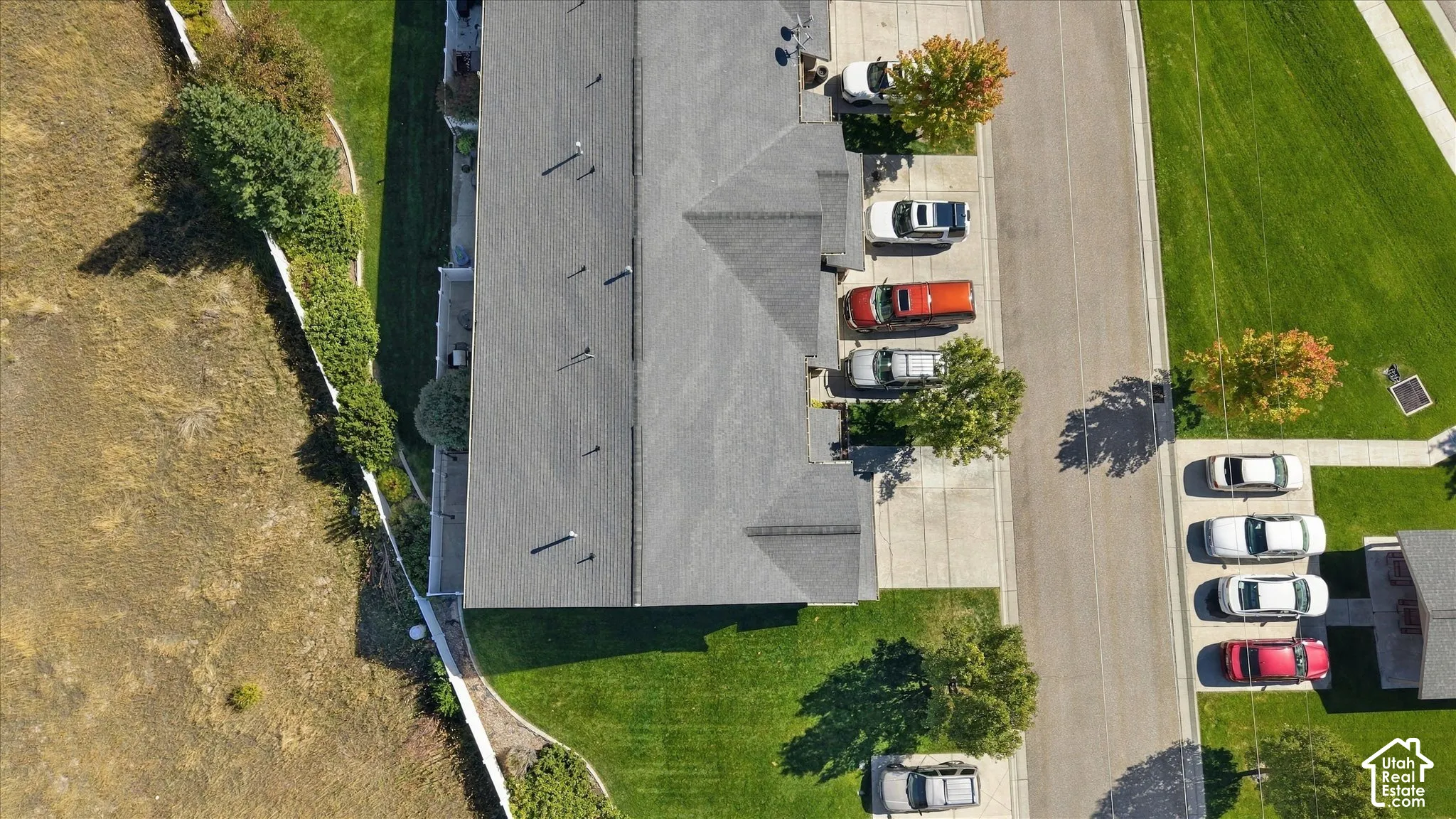 Pitched roofline with multiple vents, dedicated driveway, concrete walkways, and green lawn areas